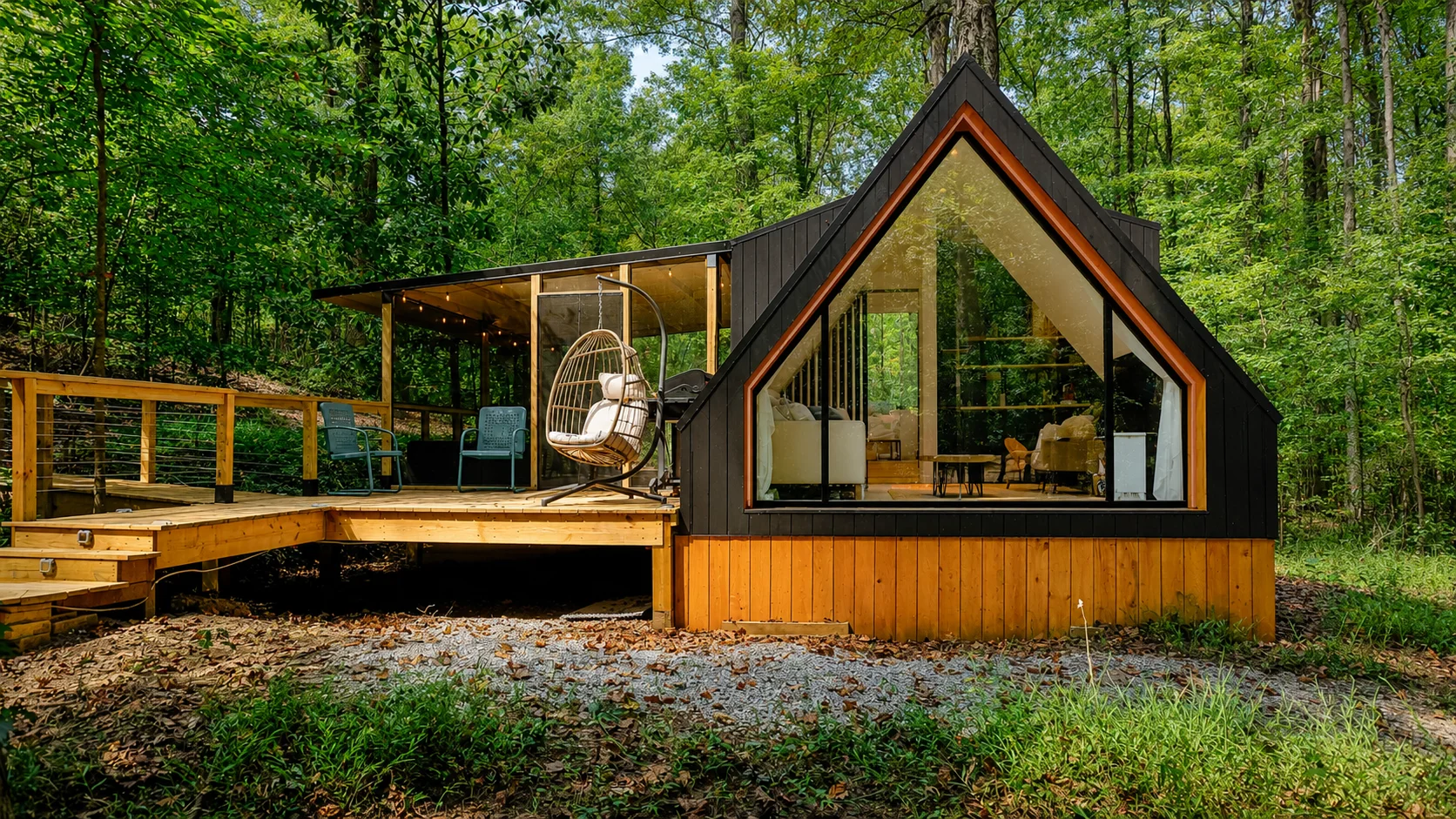 The Wild Haven A-frame cabin in sunlit forest, with its triangular glass wall, cedar deck and hanging egg chair